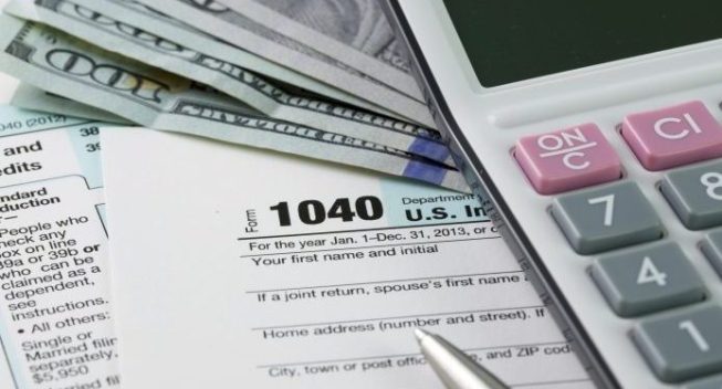 Filling out income tax forms with US dollar, calculator and pen